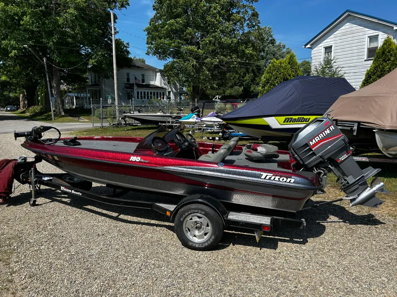 Slide: The Image of 1999 Triton 180 boat with Mariner engine on trailer, parked outdoors. - 2