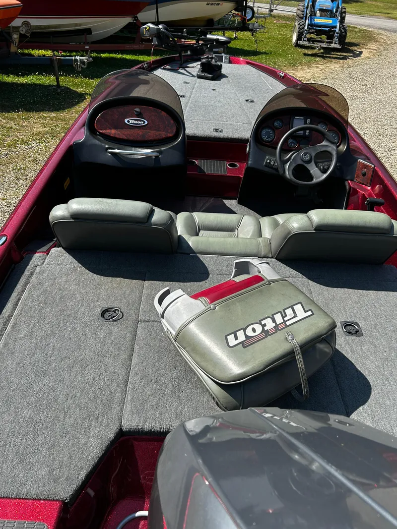 Slide: The Image of 1999 Triton 180 boat interior with gray seats and dashboard, parked outdoors. - 6
