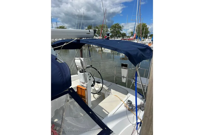Slide: The Image of 2007 Catalina 309 sailboat with blue canopy docked at marina under cloudy sky. - 12