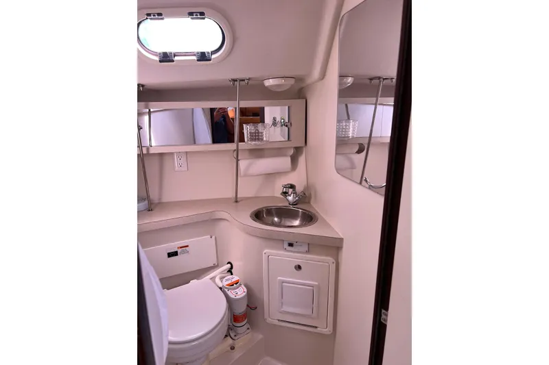 Slide: The Image of Compact bathroom in a 2007 Catalina 309 sailboat, featuring a sink, toilet, and mirror. - 29