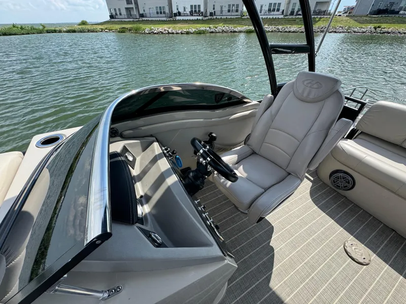 Slide: The Image of 2016 Harris Solstice DC 250 boat interior with steering wheel and comfortable seating by the water. - 11
