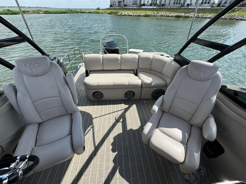 Slide: The Image of 2016 Harris Solstice DC 250 boat interior with plush seating on a calm lake. - 15