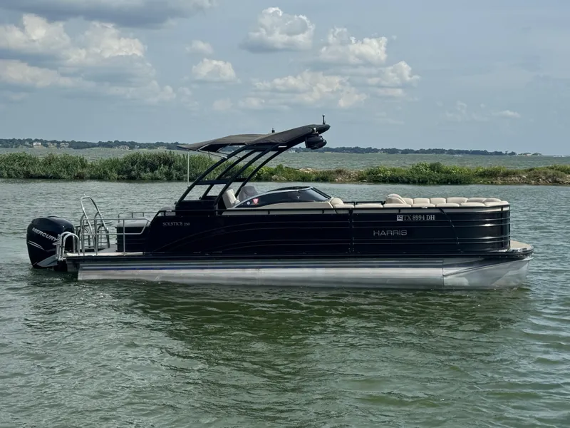 Slide: The Image of 2016 Harris Solstice DC 250 pontoon boat on a lake under a cloudy sky. - 3
