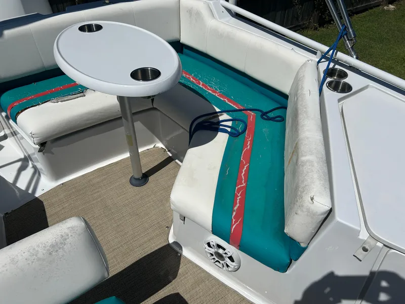 Slide: The Image of 1998 Bayliner Rendevous 26 boat interior with worn teal and red seating, round table, and cup holders. - 13