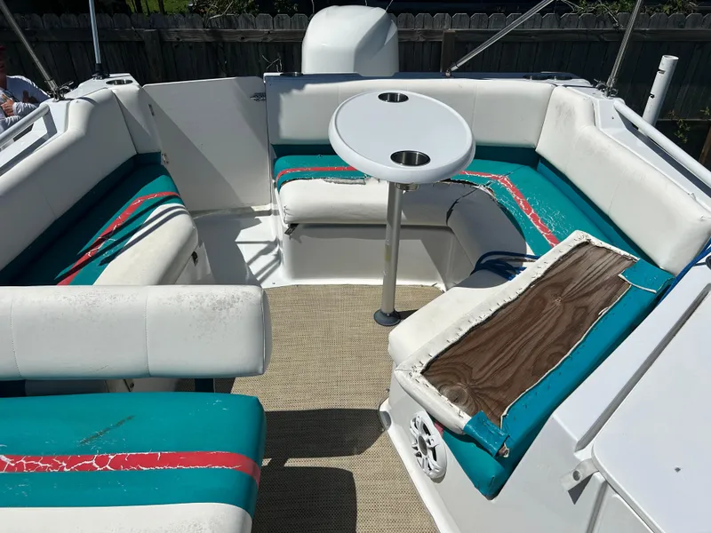 Slide: The Image of 1998 Bayliner Rendevous 26 boat interior with teal and red seating, round table, and speaker. - 15
