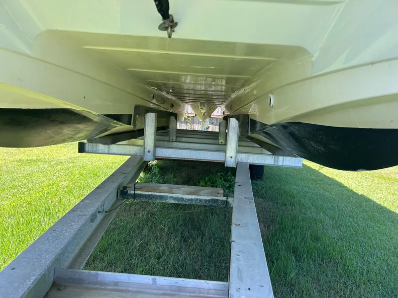 Slide: The Image of 1998 Bayliner Rendevous 26 boat on trailer, viewed from below, on grassy area. - 17