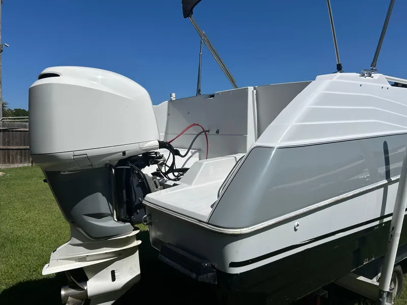 Slide: The Image of 1998 Bayliner Rendevous 26 boat with outboard motor, parked on grass under clear blue sky. - 5