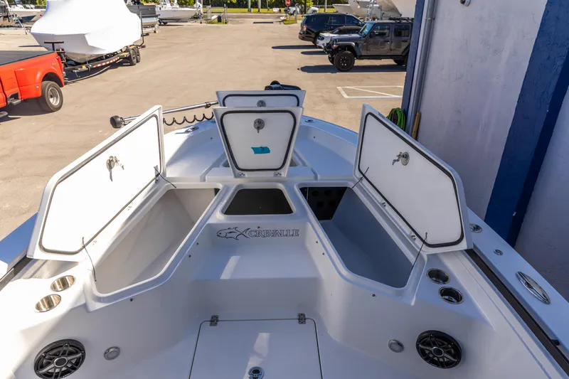 Slide: The Image of 2026 Crevalle 26 HCO boat with open storage compartments in a marina setting. - 16