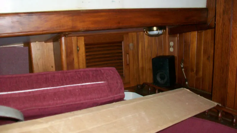Slide: The Image of Interior of 1976 Tayana 37 sailboat with wooden paneling and maroon seating. - 11