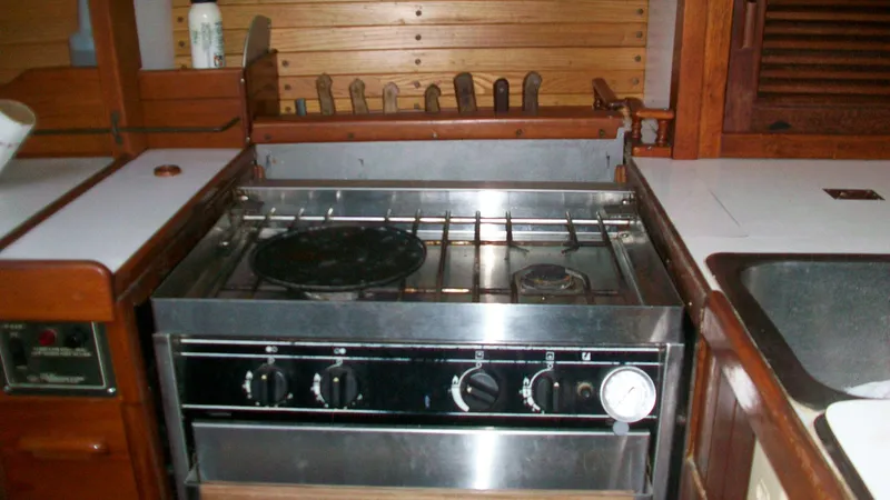 Slide: The Image of 1976 Tayana 37 yacht kitchen with stainless steel stove and wooden cabinetry. - 12