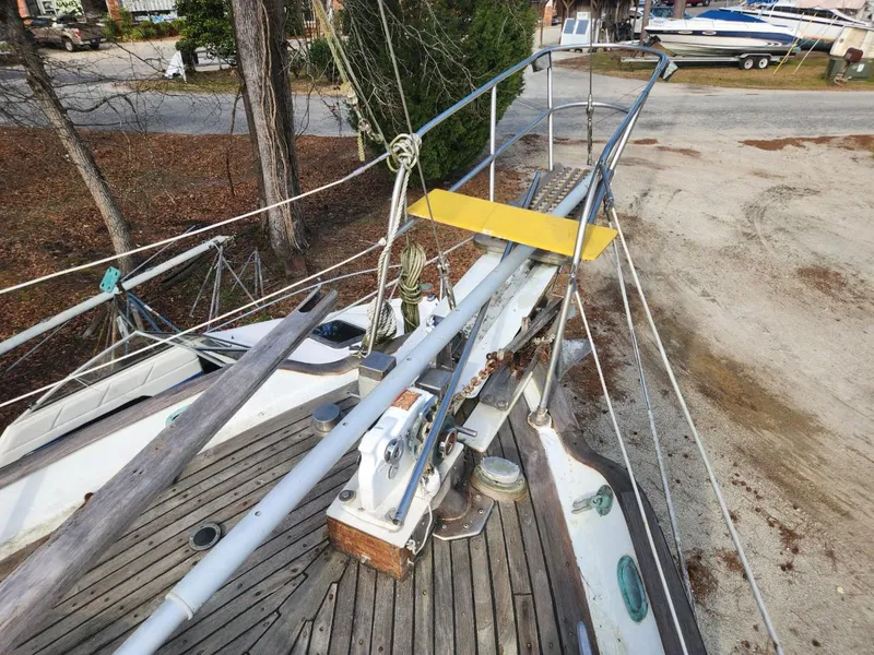 Slide: The Image of 1976 Tayana 37 sailboat deck with rigging and wooden details, docked near trees. - 20