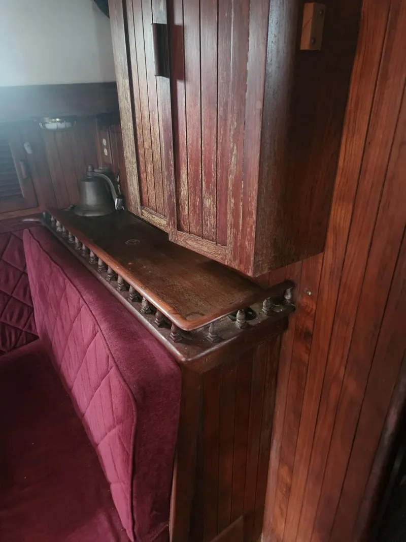 Slide: The Image of Interior of a 1976 Tayana 37 sailboat with wooden cabinetry and maroon upholstery. - 25