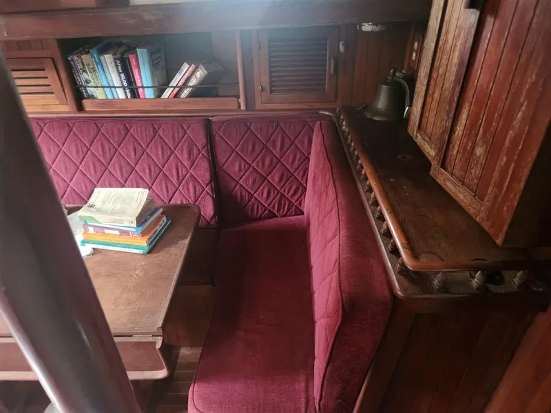 Slide: The Image of Cozy 1976 Tayana 37 sailboat interior with red cushioned seating and bookshelves. - 27
