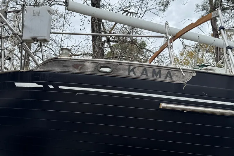 Slide: The Image of 1976 Tayana 37 sailboat named "Kama" with dark hull and rigging. - 35