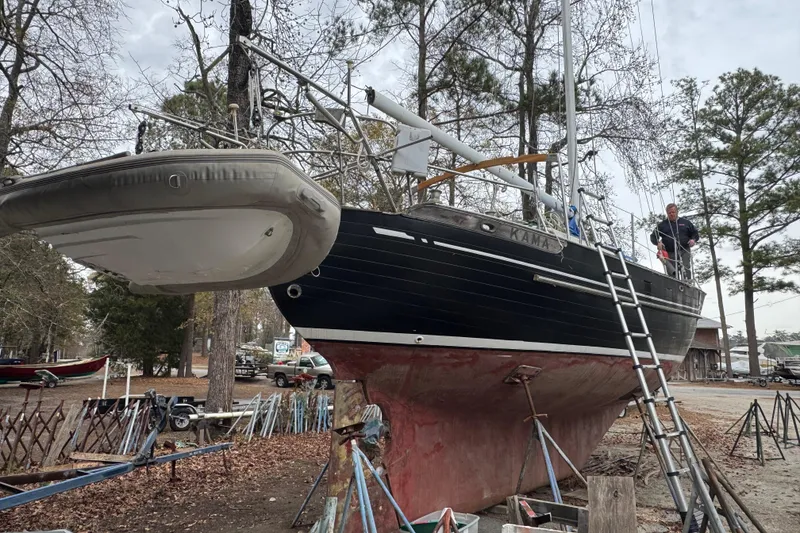 Slide: The Image of 1976 Tayana 37 sailboat on land with ladder and inflatable dinghy nearby. - 36