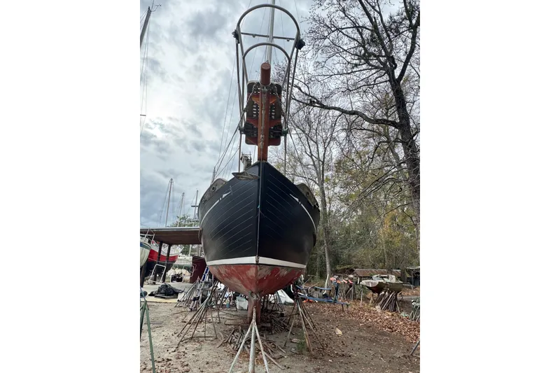 Slide: The Image of 1976 Tayana 37 sailboat on stands, surrounded by trees and overcast sky. - 37
