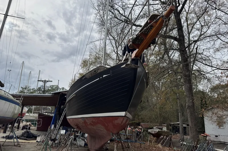 Slide: The Image of 1976 Tayana 37 sailboat on dry dock, surrounded by trees and other boats. - 38