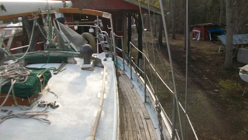 Slide: The Image of 1976 Tayana 37 sailboat docked near a wooded area with visible deck details. - 4