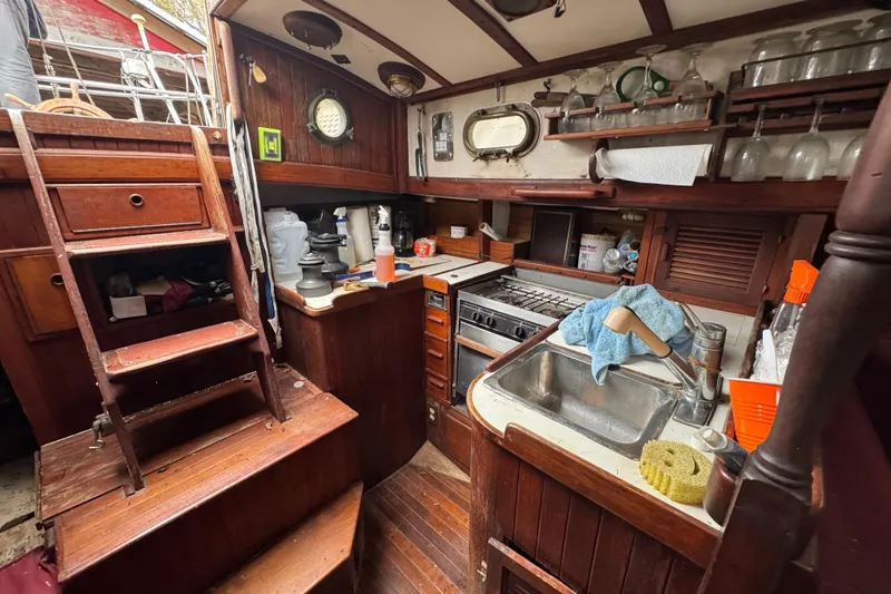 Slide: The Image of Interior of a 1976 Tayana 37 sailboat galley with wooden cabinetry and nautical decor. - 44