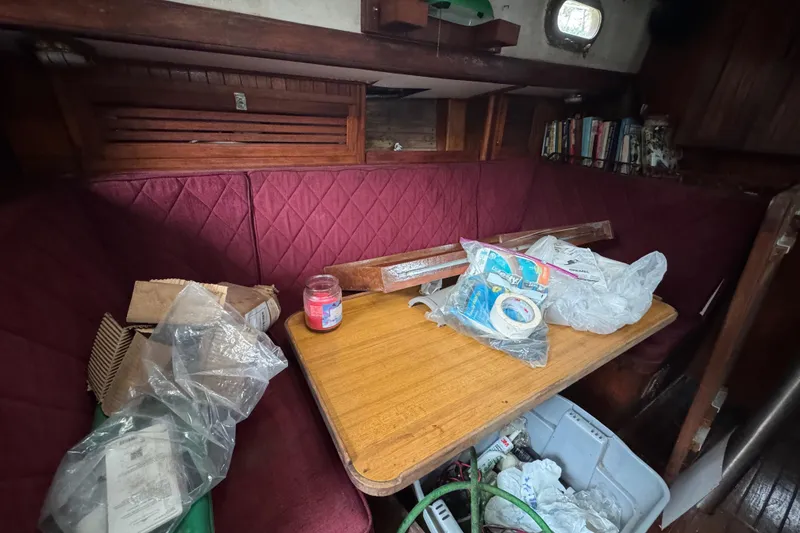 Slide: The Image of Interior of a 1976 Tayana 37 sailboat with cluttered table and red seating. - 45