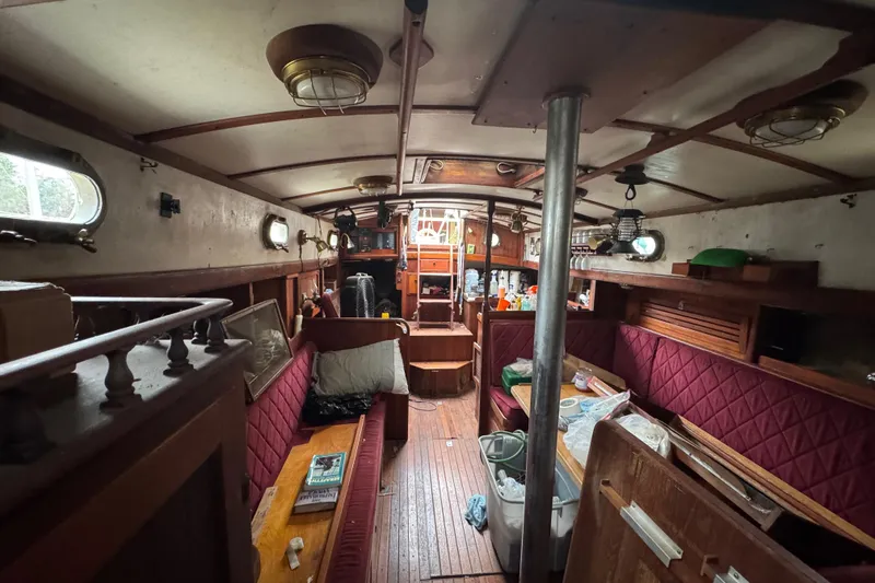 Slide: The Image of Interior of a 1976 Tayana 37 sailboat with wooden furnishings and red upholstery. - 51