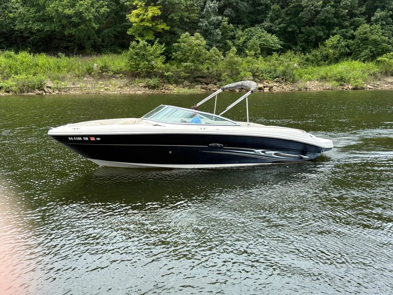 Slide: The Image of 2004 Sea Ray 220 Select boat cruising on a calm lake with lush green shoreline. - 10