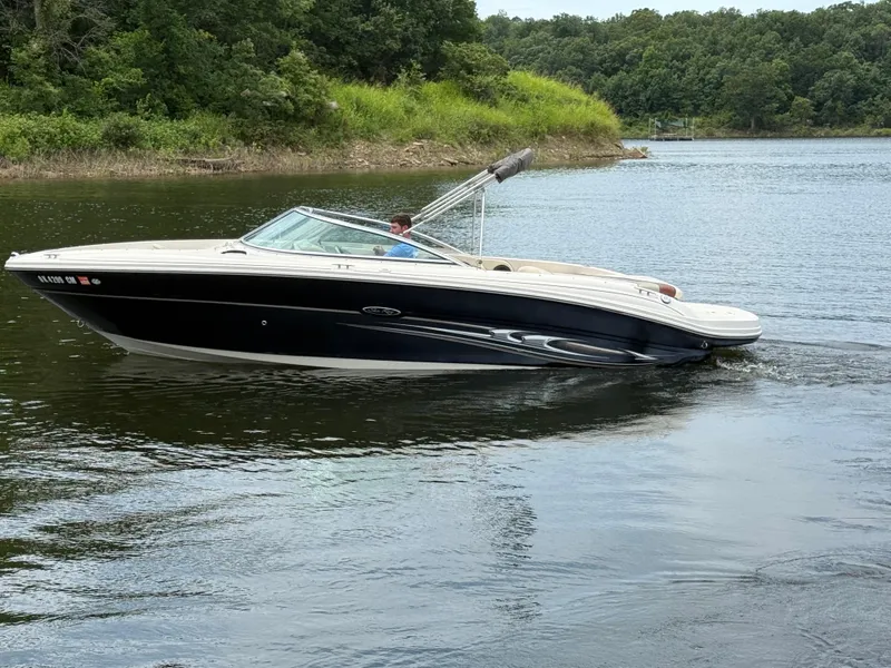Slide: The Image of 2004 Sea Ray 220 Select boat cruising on a calm lake with lush green shoreline. - 5