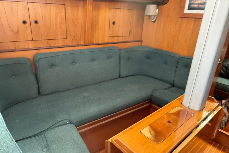 Slide: The Image of Interior of 1985 Beneteau First 375 sailboat with green cushioned seating and wooden cabinetry. - 15
