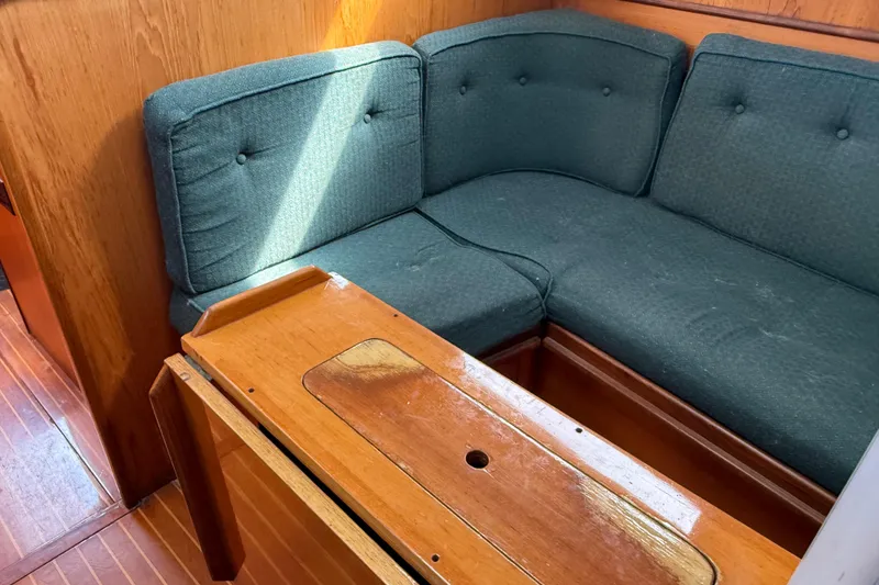 Slide: The Image of Interior of 1985 Beneteau First 375 sailboat with green cushioned seating and wooden table. - 20