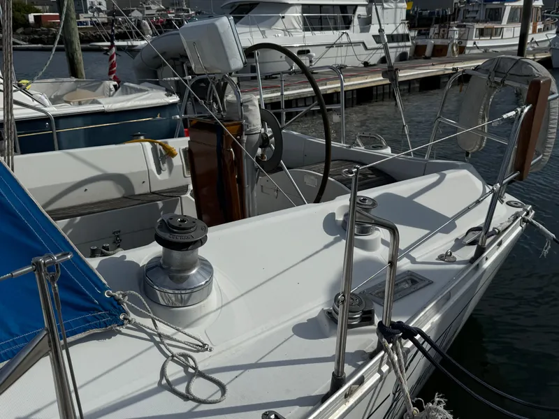 Slide: The Image of Sailboat Beneteau First 375, 1985 model, docked at marina with visible winches and steering wheel. - 4