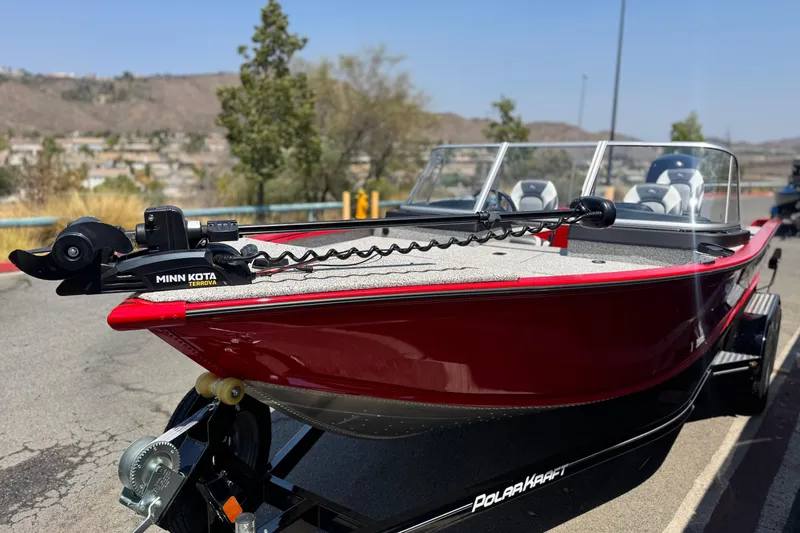 Slide: The Image of Red Apex Outlander V2010 boat, 2024 model, with Minn Kota motor, parked outdoors. - 3