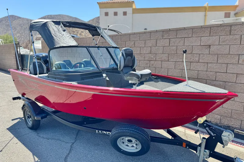 Slide: The Image of 2024 Lund 1650 Rebel XL Sport boat, red, parked on trailer, sunny day. - 1
