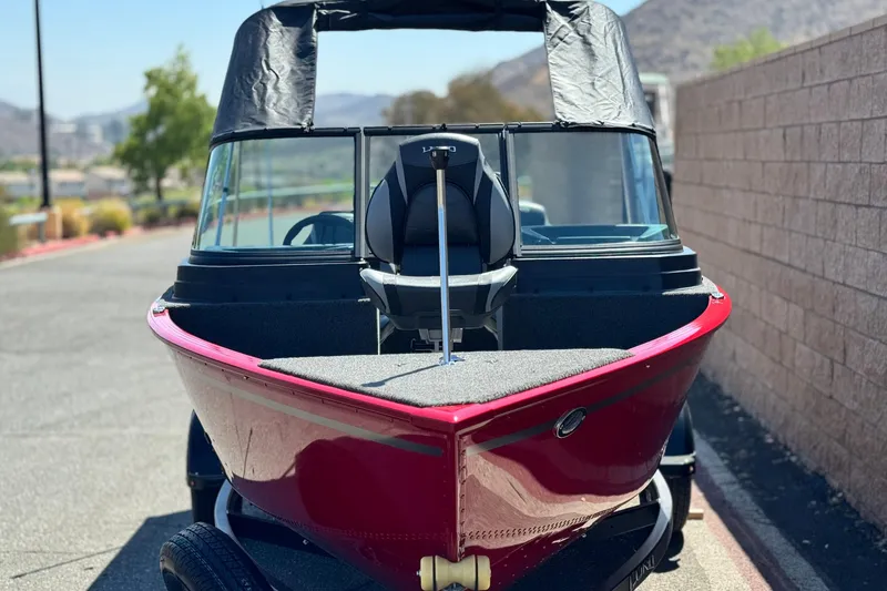 Slide: The Image of 2024 Lund 1650 Rebel XL Sport boat, red exterior, parked outdoors on a sunny day. - 2