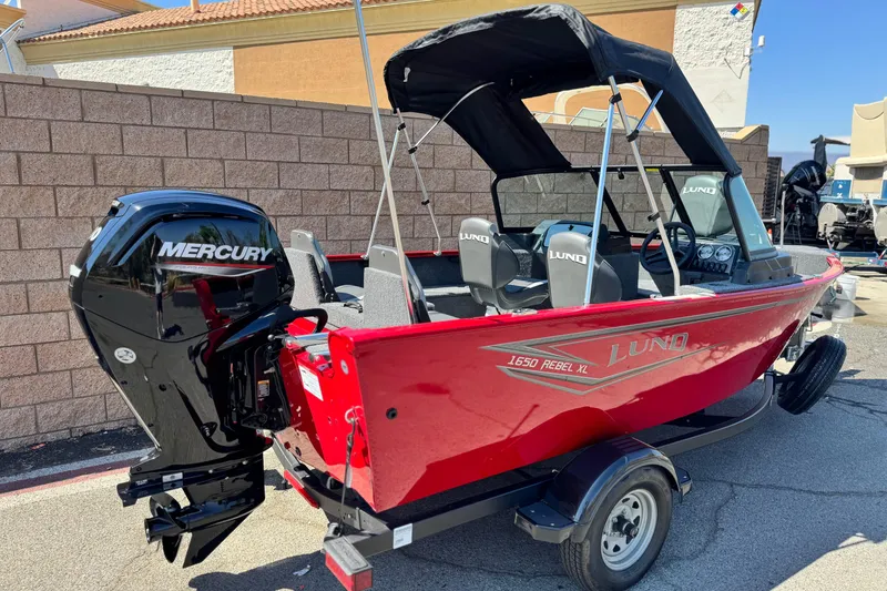 Slide: The Image of 2024 Lund 1650 Rebel XL Sport boat with Mercury engine, red exterior, parked outdoors. - 5