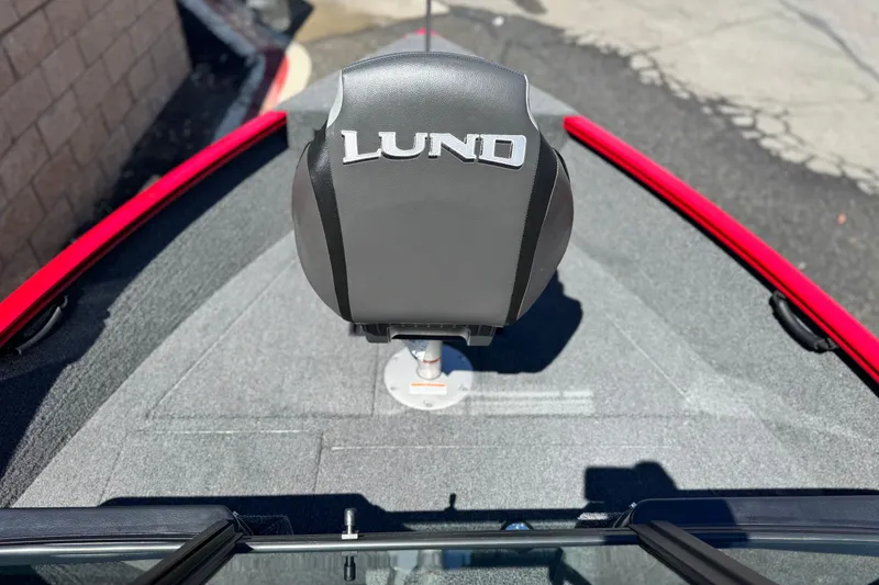 Slide: The Image of 2024 Lund 1650 Rebel XL Sport boat seat, gray with red accents, outdoor setting. - 8