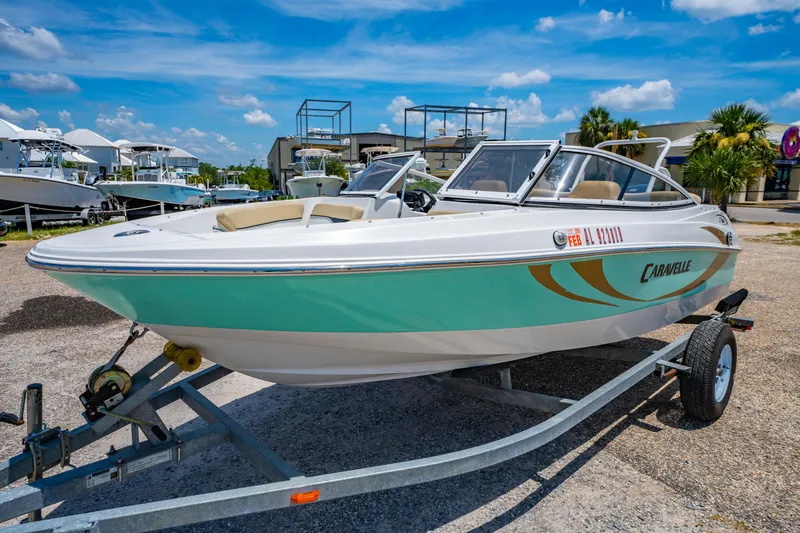 Slide: The Image of 2018 Caravelle 17 EBo Bowrider boat on trailer, parked outdoors under blue sky. - 6