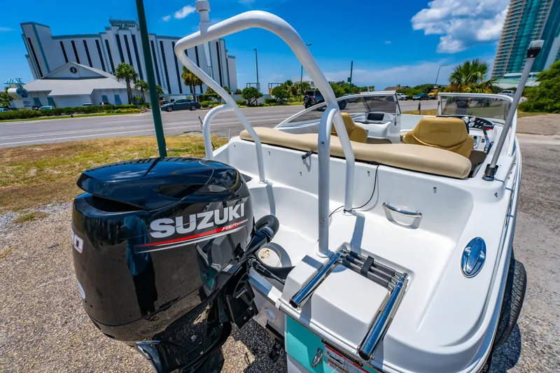 Slide: The Image of 2018 Caravelle 17 EBo Bowrider with Suzuki outboard motor, parked near a modern building. - 7
