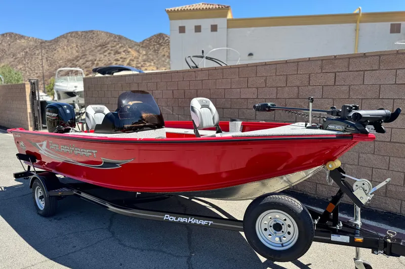 Slide: The Image of 2023 Apex Polar Kraft V186 boat in vibrant red on a trailer, parked outdoors. - 2