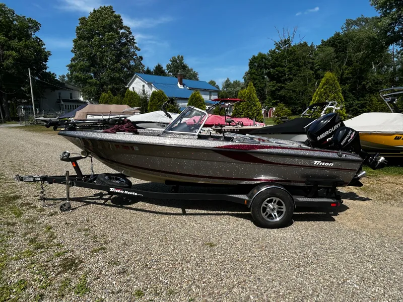 Slide: The Image of 2013 Triton 186 Fishunter boat on trailer, parked outdoors on gravel. - 1