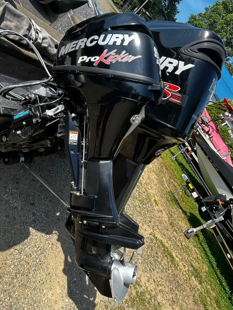 Slide: The Image of 2013 Triton 186 Fishunter with Mercury Pro Kicker outboard motor, parked on gravel. - 10