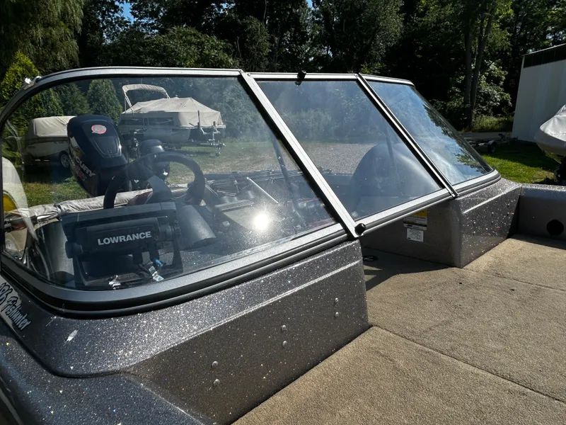 Slide: The Image of 2013 Triton 186 Fishunter boat with windshield and Lowrance equipment, parked outdoors. - 6