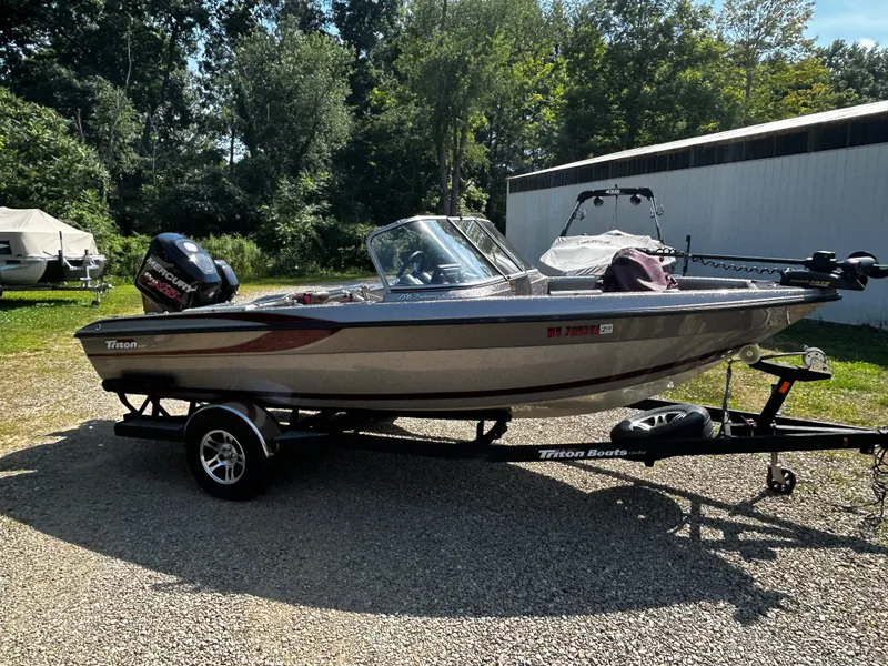 Slide: The Image of 2013 Triton 186 Fishunter boat on trailer, parked outdoors with trees in background. - 7