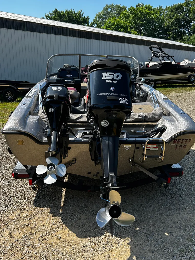 Slide: The Image of 2013 Triton 186 Fishunter boat with dual outboard motors, parked outdoors. - 9