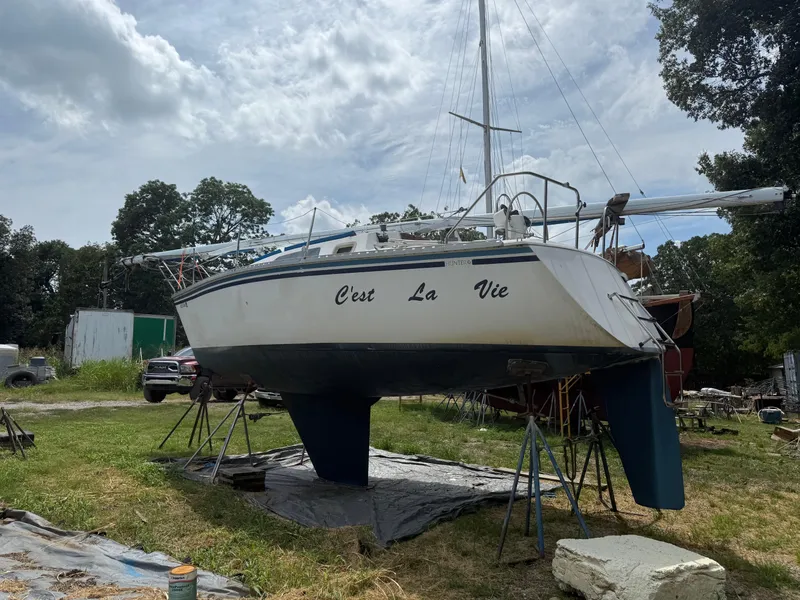 Slide: The Image of 1986 Hunter 28.5 sailboat "C'est La Vie" on stands in a grassy yard. - 4