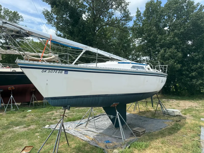 Slide: The Image of 1986 Hunter 28.5 sailboat on stands, surrounded by trees, under a clear sky. - 5