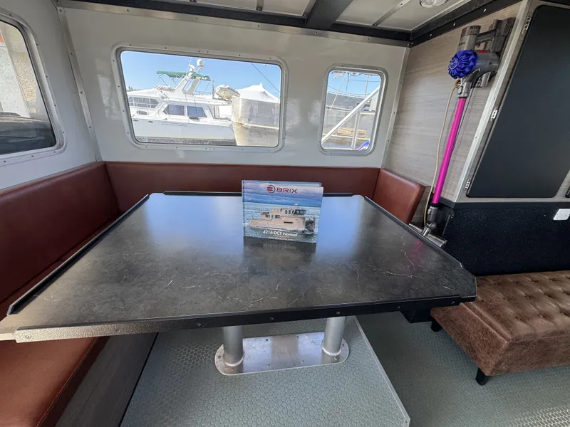 Slide: The Image of Interior of 2020 Aluminum Cruiser 42' Trawler with table, brochure, and vacuum cleaner. - 12