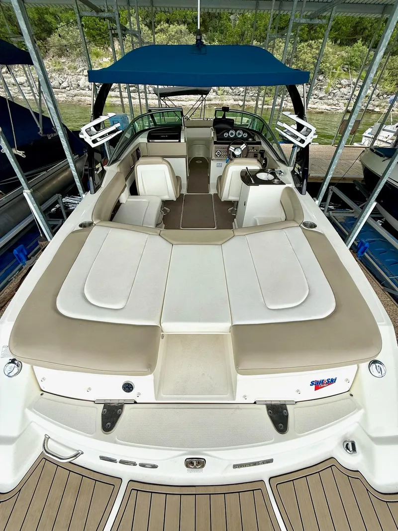 Slide: The Image of 2013 Sea Ray 250 SLX boat interior with seating and controls, docked under a canopy. - 25