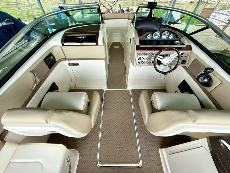 Slide: The Image of Interior of a 2013 Sea Ray 250 SLX boat with beige seating and dashboard controls. - 29