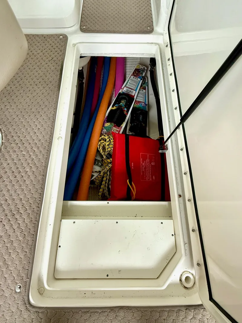 Slide: The Image of Storage compartment in a 2013 Sea Ray 250 SLX boat, containing pool noodles and equipment. - 31
