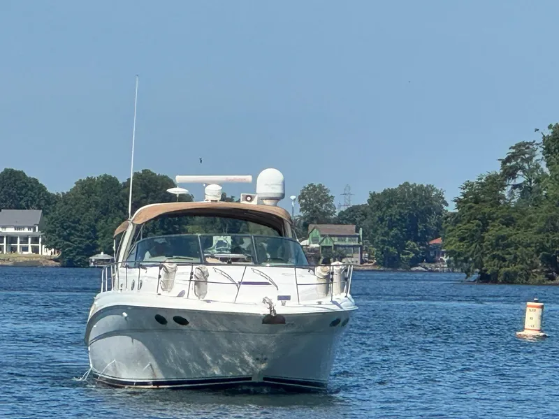 The Image of 2001 Sea Ray 380 Sundancer yacht cruising on a serene lake with lush greenery. - 1